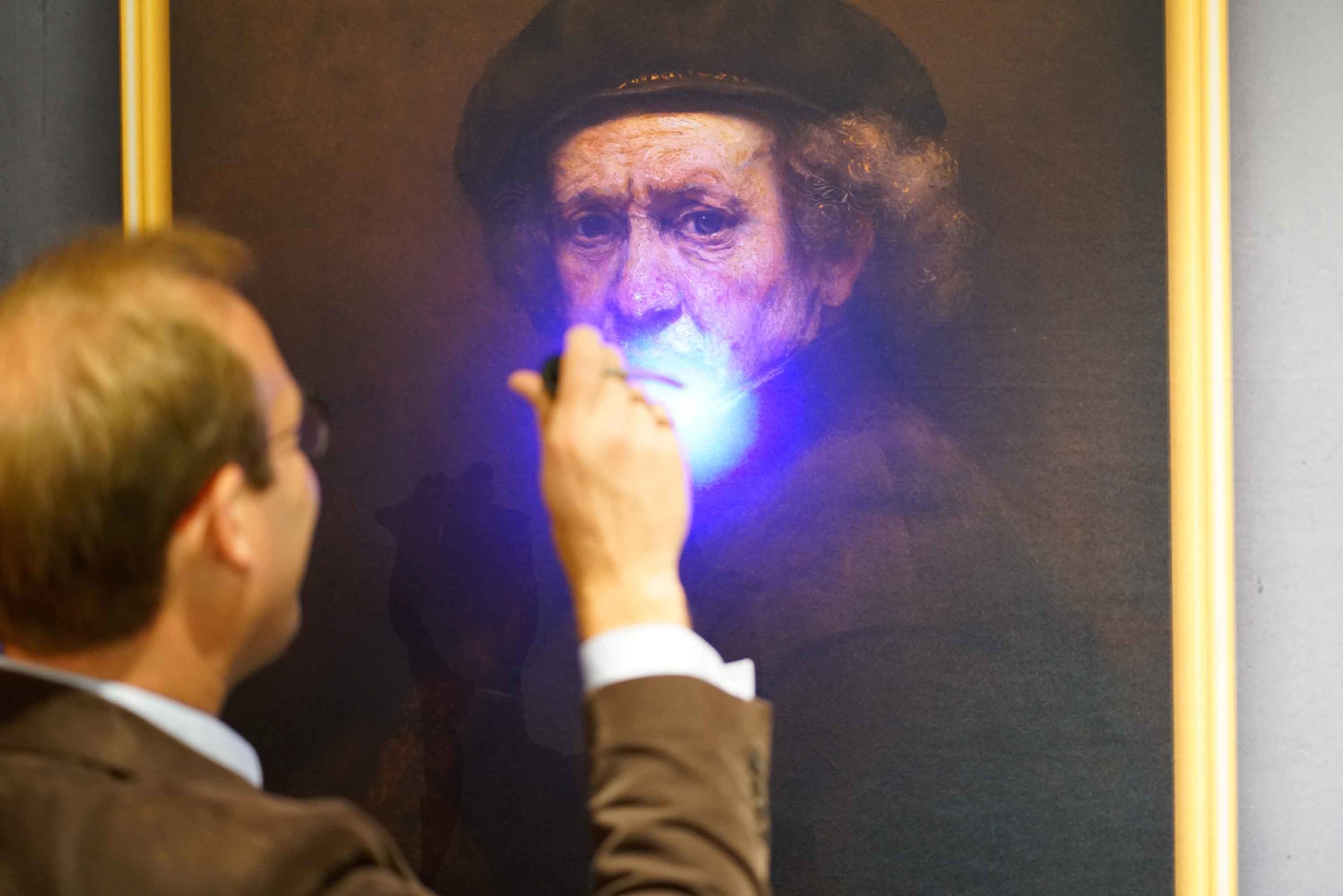 Un homme analyse une œuvre d'art avec une lampe UV lors d'un Serious Game pour entreprise
